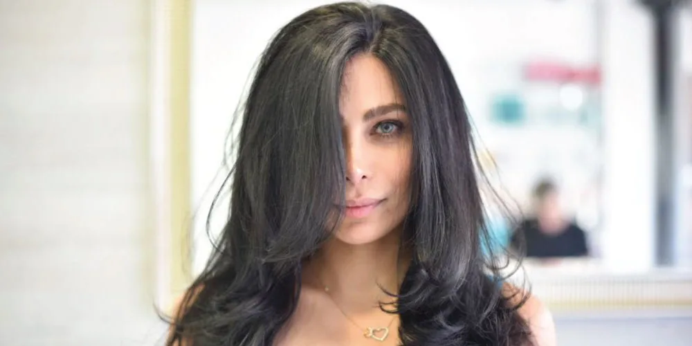 women’s hairstyling woman with long black hair covering half her face