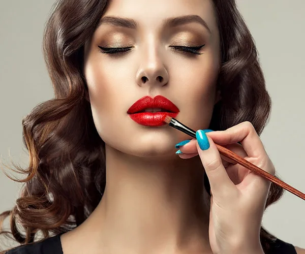 makeup consultation lady applying red lipstick to a woman's lips with lipstick brush