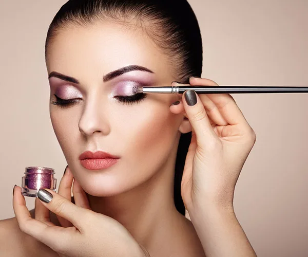makeup consultation applying purple eyeshadow to a lady's eyebrows