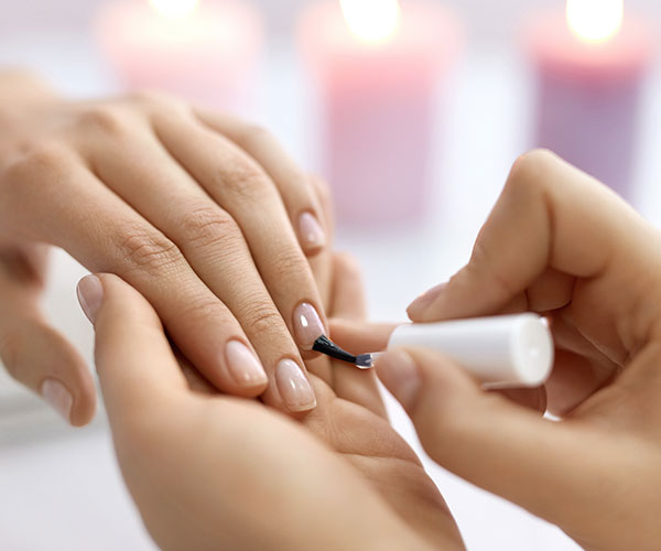putting nail polish on a lady's hand