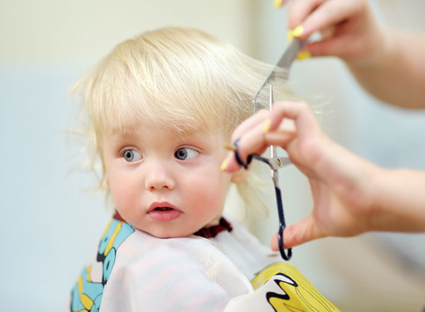 blond toddler having a hair cut