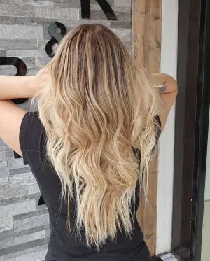 woman in black t-shirt with dark hair with blonde balayage treatment