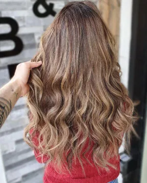 woman in red jumper with brown hair after blonde balayage treatment