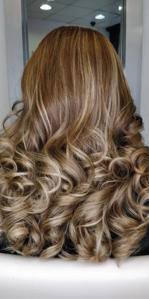 balayage hair treatment woman with blonde and brown curly hair after balayage treatment