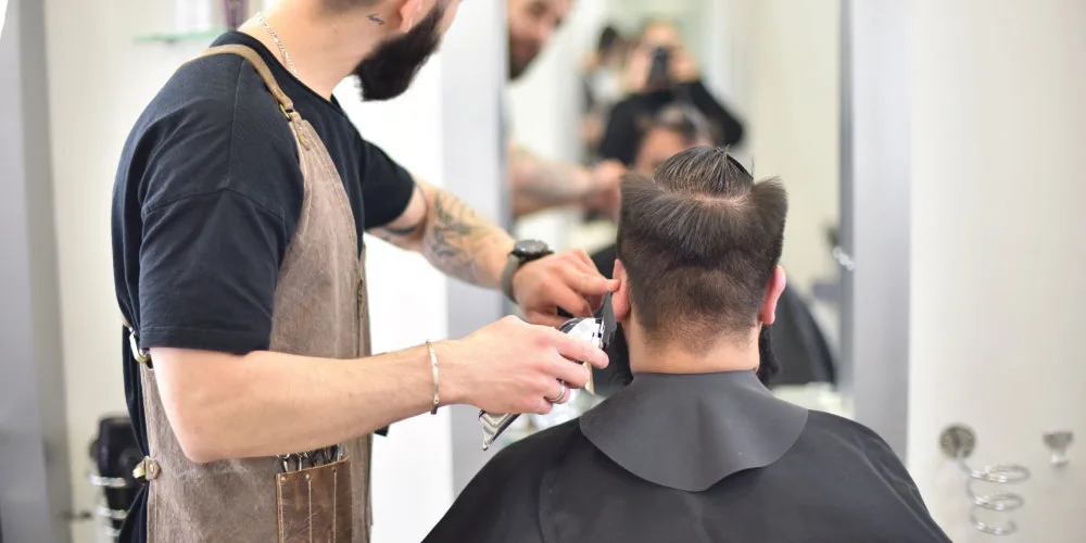 men’s hairstyling Hairdresser giving a man a haircut with a razor