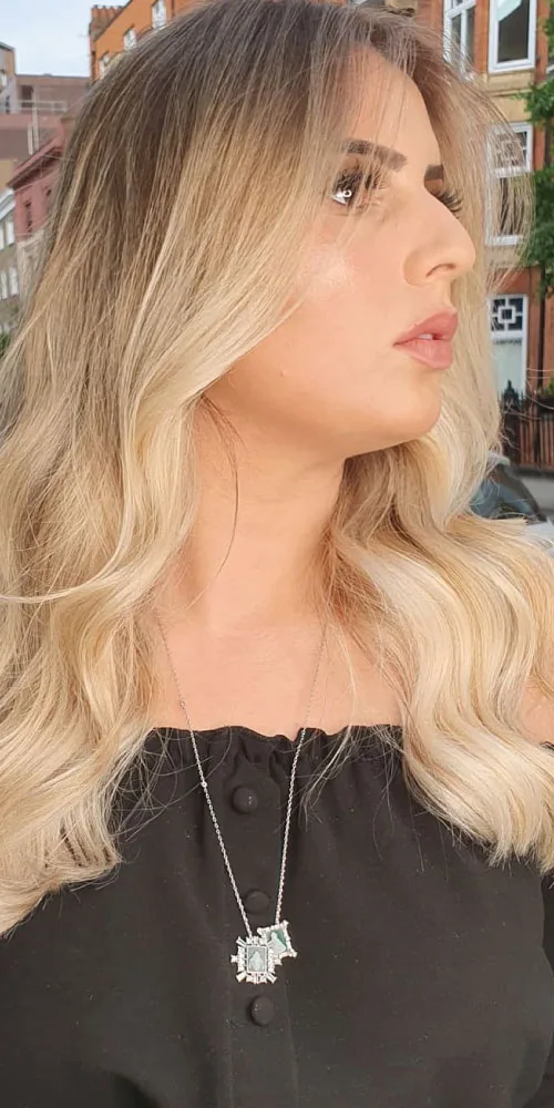 blonde balayage Woman in black top with blonde hair after balayage treatment