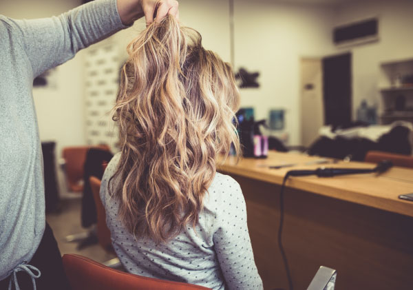 Woman in hair salon with blonde hair after balayage treatment