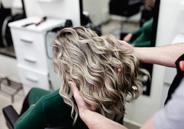 Woman in hair salon with blonde hair after balayage treatment