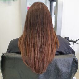 woman with long brown hair sitting in hairdressing chair