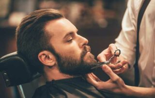 man having beard trimmed at barbers